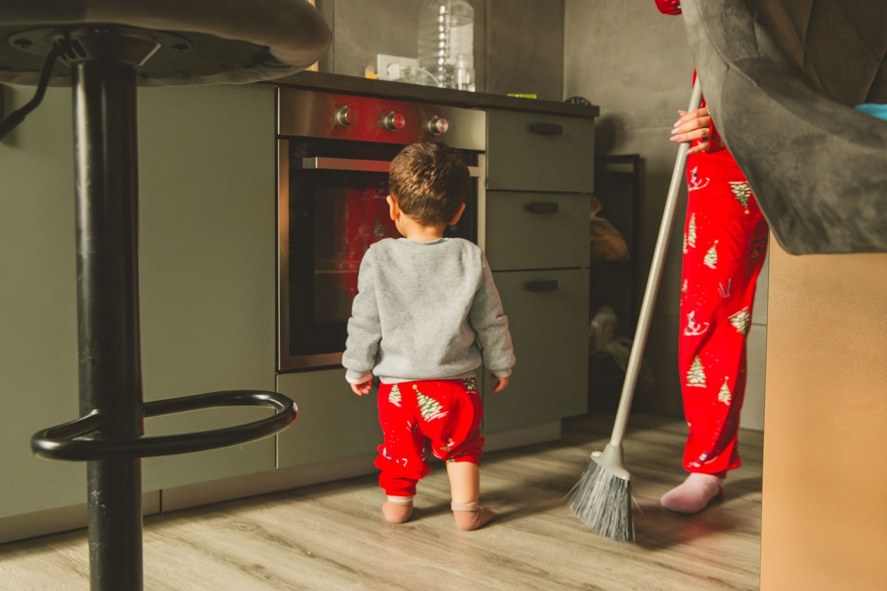 Cute toddler and adult in a kitchen wearing matching Christmas pajamas.
